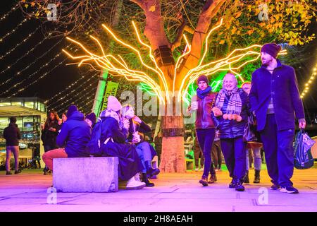 London, Großbritannien. 28th. November 2021. Die Londoner sitzen und spazieren auf den neonbeleuchteten Baumdächern, die dieses Jahr Teil der Southbank Winter Lights sind. Das kostenlose Display kann täglich von der Dämmerung bis zum 11,30pm. Januar bis zum 9th. Januar 2022 besichtigt werden. Kredit: Imageplotter/Alamy Live Nachrichten Stockfoto