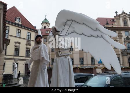 Prag, Tschechische Republik. 28th. November 2021. Die Künstler sahen die Installation der Engelsflügel vor Beginn der Angelikprozession. Drei als Engel gekleidete Künstler gehen auf Stelzen und wünschen den Menschen am ersten Adventssonntag in Prag frohe Weihnachten. Kredit: SOPA Images Limited/Alamy Live Nachrichten Stockfoto