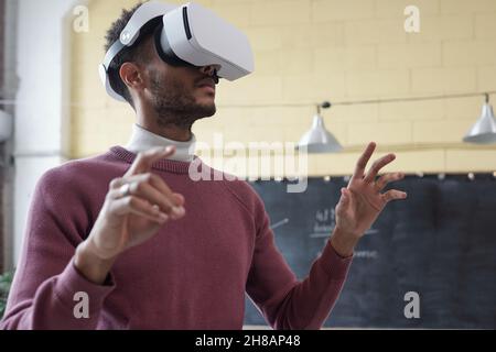 Junge moderne Geschäftsmann in Virtual-Reality-Headset Vorbereitung oder durch Online-Präsentation Stockfoto