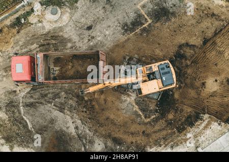 Bagger gräbt Grubenfundament. Erdarbeiten in Ausgrabungen auf der Baustelle, Luftaufnahme von oben. Stockfoto