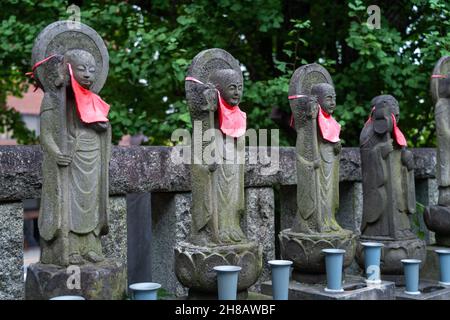 Statuen von buddhas, die mit roten Lätzchen verziert sind, befinden sich im Honryuin-Tempel, einem buddhistischen Schrein, der dem gott Kangiten in Asakusa, Tokio, Japan, gewidmet ist. Der Tempel ist bekannt für die Darbringung von Daikon Radieschen, die im Gebet angeboten werden. Stockfoto
