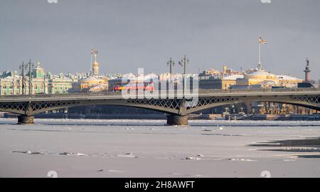 Der Panoramablick auf die Winterstadt Sankt-Petersburg, gefrorenen Newa-Fluss, der rote Touristenbus auf Blagoweschtschensky Brücke, Winterpalast, Admiralität Stockfoto