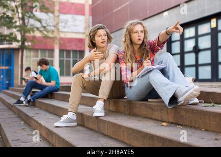 Mädchen zeigt ihren Finger auf Kerl auf der Straße während der Pause in der Hochschule Stockfoto