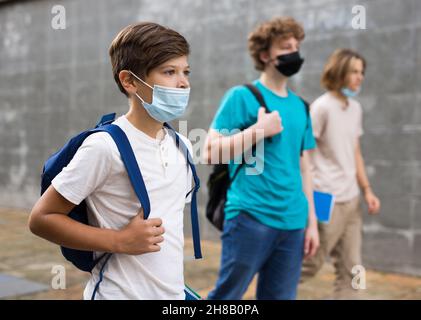 Teen junge in Schutzmaske Spaziergang entlang Sommer Straße nach Abschluss College-Unterricht in der Nähe Stockfoto