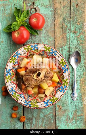 Hausgemachte Chorba-Suppe mit Lammfleisch auf Knochen, Kartoffeln, Karotten und getrockneten Aprikosen in bunten Teller vertikal Stockfoto