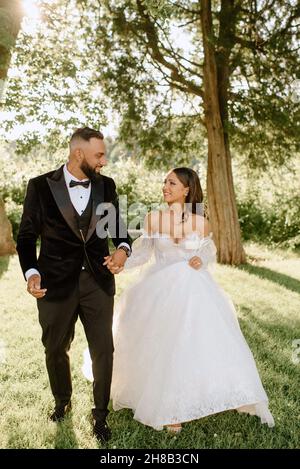 Lächelnde Braut und Bräutigam gehen im Park Stockfoto