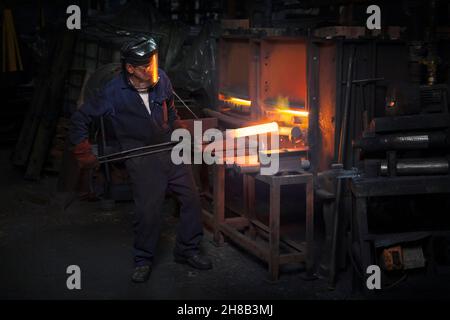 Arbeiter vor Heizung Stahl Billet zum Schmieden in Upsetter zu schmieden Stockfoto