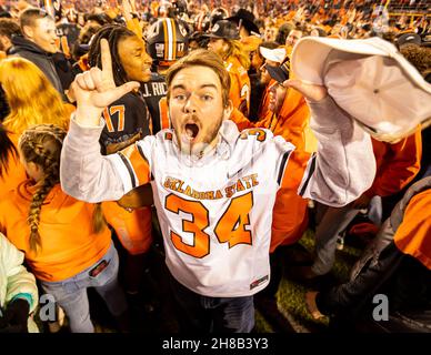 Stillwater, Oklahoma, USA. 27th. November 2021. Oklahoma State Cowboy-Fans stürzen sich nach dem Sieg über die Oklahoma Sooners aus dem Jahr 37-33 am Samstag, den 27. November 2021 im Boone Pickens Stadium in Stillwater, Oklahoma, ins Feld. (Bild: © Nichola Rutledge/ZUMA Press Wire) Stockfoto