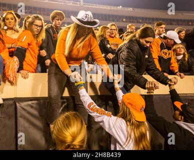 Stillwater, Oklahoma, USA. 27th. November 2021. Oklahoma State Cowboy-Fans stürzen sich nach dem Sieg über die Oklahoma Sooners aus dem Jahr 37-33 am Samstag, den 27. November 2021 im Boone Pickens Stadium in Stillwater, Oklahoma, ins Feld. (Bild: © Nichola Rutledge/ZUMA Press Wire) Stockfoto