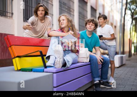 Schulkinder sitzen auf der Bank im Schulhof Stockfoto