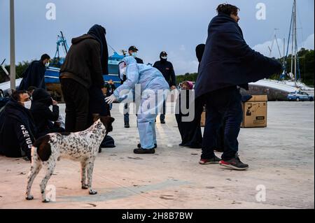 Roccella Jonica, Italien. 28th. November 2021. Am Hafen von Roccella wird ein Mitglied des Roten Kreuzes gesehen, das Migranten hilft.Fast 200 Migranten, bestehend aus Frauen und Kindern, wurden von der italienischen Küstenwache gerettet. Die Migranten wurden nach Roccella Jonica gebracht, einer Stadt am Ionischen Meer in Kalabrien. Bei der Ankunft erhielten das Rote Kreuz und der Katastrophenschutz sanitäre Hilfe, während die Behörden den Identifikationsprozess durchführten. Kredit: SOPA Images Limited/Alamy Live Nachrichten Stockfoto