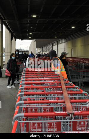 Ein Arbeiter sammelt Warenkörbe ein, während sich die Leute für den Black Friday-Verkauf in Vancouver aufmachen. Stockfoto