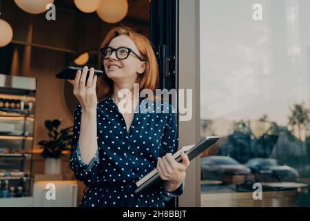 Pretty Woman spricht über den Lautsprecher über das Smartphone zeichnet Sprachnachrichten auf Stockfoto