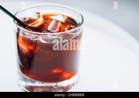 Kaltes Gebräu mit Eis und schwarzem Stroh auf weißem Hintergrund. Köstliches kaltes Getränk mit Kaffee. Stockfoto