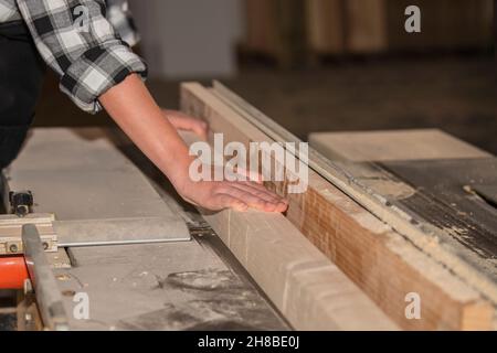 Frau, die in einer Schreinerei an Holzbearbeitungsmaschinen arbeitet Stockfoto