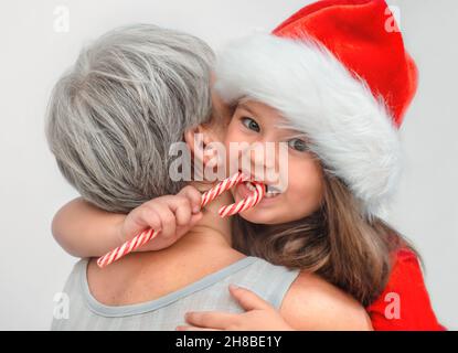 Der ältere umarmt das Kind. Enkelin isst Zuckerrohr, während Oma nicht schaut Stockfoto