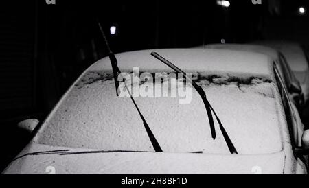 Die Scheibenwischer des Autos wurden gegen das Einfrieren im Schnee zurückgelassen. Nachtansicht der Winterbedingungen. Stockfoto