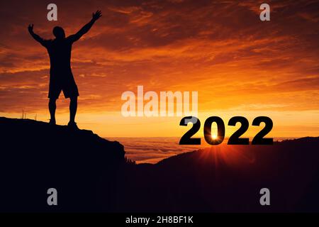 Mann Silhouette auf der Bergspitze beobachten den Sonnenaufgang und 2022 Jahre beim Feiern. Stockfoto