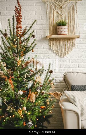 Weihnachten und Neujahr Dekorationen in Boho Interior Design mit Sofa und Macrame Paneele. Stockfoto