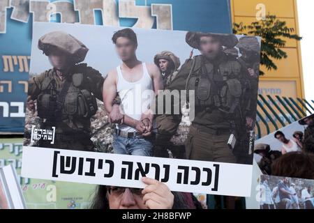 WESTJORDANLAND, ISRAEL – 28. NOVEMBER: Ein Anhänger der linken Peace Now-Bewegung hält ein Schild mit einem Foto, auf dem israelische Soldaten einen Palästinenser festnehmen, mit der Aufschrift: „so sieht die Besatzung aus“, während einer Demonstration gegen den Besuch des israelischen Präsidenten Isaac Herzog in der Ibrahimi-Moschee, Die Juden nennen sie die Höhle von Machpelah am Eingang der israelischen Siedlung Kiryat Arba in der Nähe der palästinensischen Stadt Hebron am 28. November 2021 im Westjordanland, Israel. Präsident Herzog besuchte die heilige Stätte, um die erste Chanukka-Kerze anzuzünden, die ein Teil der je ist Stockfoto