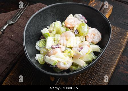 Salat mit Garnelen, Avocado, Tomaten und Mayonnaise auf dem Salat-Set, mit Sauce Apfel und Traube, auf altem dunklen Holztisch Stockfoto