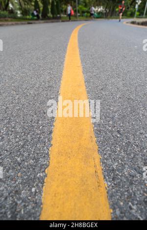 Nahaufnahme der gelben Linie auf dem öffentlichen Park mit Menschen Bewegung und Radfahren für eine gute Gesundheit Hintergrund Stockfoto