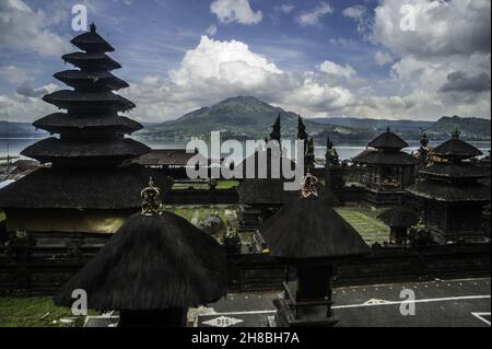 Ein Tempel des Dorfes Terunyan mit dem Batur Vulkan als Hintergrund, der vom See vom Terunyan Friedhof auf der Bali Insel, Indonesien, abgespärt wurde. Foto aufgenommen am 3. November 2016. Die Tradition der terunischen Einäscherung ist ein immaterielles Erbe des Stammes der Bali Aga (Ureinwohner der Insel Bali), das sich an die natürlichen Merkmale des pazifischen Feuerrings in der jungsteinzeit anpasste und bis heute erhalten bleibt. Die Einäscherung der Tradition der Terunyan geht davon aus, den Todeskörper zu lassen, ohne im Waldfleck der Weihrauchvegetation begraben zu werden, weg von der Hauptsiedlung, sagte ein Eingeborener der Terunyan Villa Stockfoto