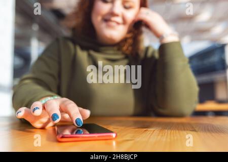 Eine lächelnde Frau tippt auf den Telefonbildschirm. Nahaufnahme von Hand und Telefon. Das Konzept der sozialen Medien. Stockfoto