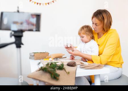 Portrait der jungen Mutter und ihrer kleinen Tochter machen Spielzeug für die Weihnachtsferien. Das Konzept des Video-Streamings. Stockfoto