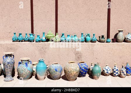 Traditionelle iranische Souvenirs - bunte Tonkrug und -Krug, Yazd, Iran. Tonkannen in verschiedenen Formen von grünen und blauen Farben auf einem Regal in der Nähe der adobe Stockfoto