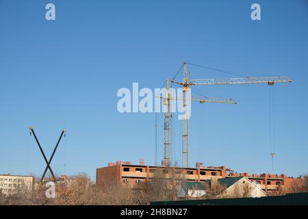 Zwei Hochhäuser und zwei kleine Krane sind beteiligt Bau Wohngebäude. Stockfoto