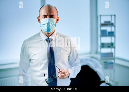 Müder Wissenschaftler in einer Schutzmaske, die im Labor steht. Stockfoto