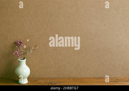 Vase mit trockenen Blumen auf Holztisch. Braune Wand Hintergrund. Home Interieur Stockfoto