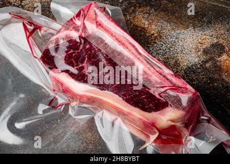 Frisches, riesiges und appetitliches Clubsteak im Vakuumverpackungsset, auf altem dunklen rustikalen Hintergrund Stockfoto