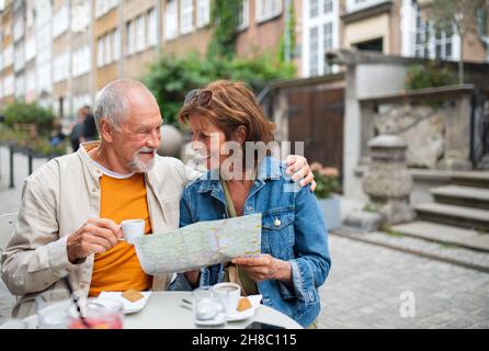 Porträt von glücklichen älteren Paar Touristen sitzen und mit Karte im Freien in der Stadt. Stockfoto