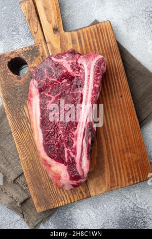 Frisches, riesiges und appetitliches, trocken gealtertes Club-Steak-Set, auf grauem Steingrund, von oben aus flache Laie Stockfoto