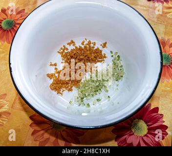 Weiße Emaille-Schüssel mit Zutaten zum Backen von Stollen auf Einem Tisch, Zitronenschale und Orangenschale Stockfoto