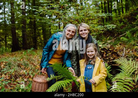 Kleines Mädchen mit Mutter und Großmutter auf Spaziergang Outoors im Wald, Blick auf die Kamera. Stockfoto