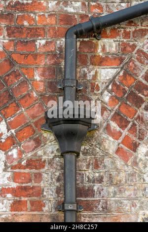 Regenwasserbehälter aus Gusseisen auf Dachrinnen in einem historischen Haus, architektonische Details in einem roten Backsteingebäude mit alten, alten Metallrinnen Stockfoto