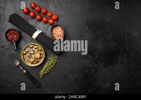 Rohzutaten hausgemachte Pasta Spaghetti mit Muscheln Set, auf schwarzem dunklen Stein Tischhintergrund, Draufsicht flach liegend, mit Platz für Text Stockfoto