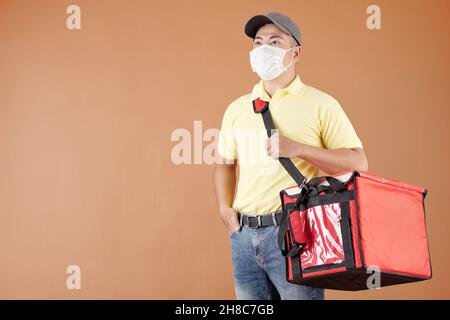 Porträt eines asiatischen Kuriers in Schutzmaske mit Versandtasche Stockfoto