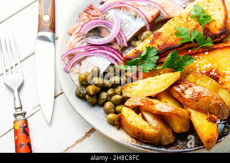 Stücke von gesalzenem Hering mit gebackenen Kartoffeln und Toast. Stockfoto