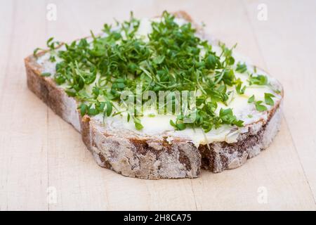 Brot mit Butter und Kresse auf einem Holzbrett Stockfoto