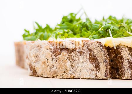 Detail von gebuttertem Brot mit Kresse auf einem Holzbrett Stockfoto