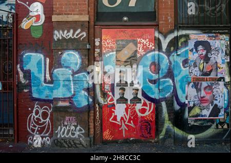 STADTLANDSCHAFT Eine Tür und eine Wand an der East Houston Street in Lower Manhattan mit Graffiti, Street Art, Postern und Tags. Stockfoto