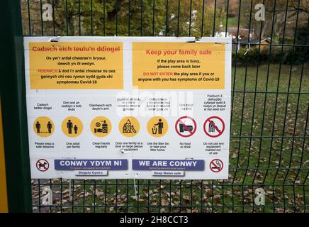 Gesundheits- und Warnhinweise auf einem Zaun zu einem Kinderspielplatz in walisisch und englisch, Stockfoto