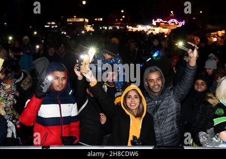 Die Bewohner der Weihnachtsgemeinschaft winken mit ihren Handy-Lichtern Fackeln, um das Einschalten der Weihnachtsbeleuchtung in Tettenhall, Wolverhampton, 2021, zu feiern Stockfoto