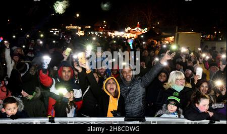 Die Bewohner der Weihnachtsgemeinschaft winken mit ihren Handy-Lichtern Fackeln, um das Einschalten der Weihnachtsbeleuchtung in Tettenhall, Wolverhampton, 2021, zu feiern Stockfoto