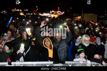 Die Bewohner der Weihnachtsgemeinschaft winken mit ihren Handy-Lichtern Fackeln, um das Einschalten der Weihnachtsbeleuchtung in Tettenhall, Wolverhampton, 2021, zu feiern Stockfoto