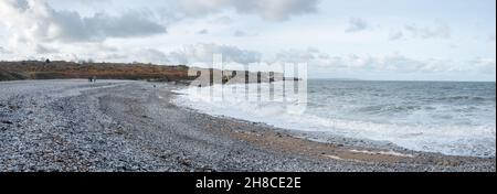 Die Familie genießt einen Spaziergang am Kiesstrand in Penmon, Anglesey, Wales Stockfoto